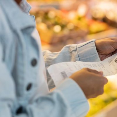 Woman looking at receipts in supermarket. Image, Adobe